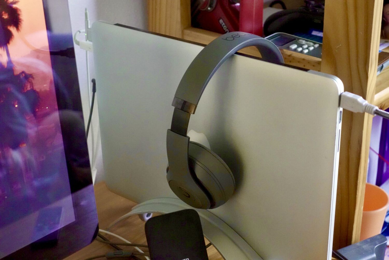 Picture of my laptop in a vertical clamshell stand with a pair of headphones resting on it